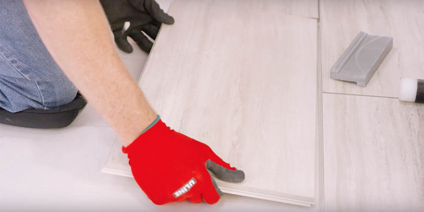 Installer with red gloves installing Daltile's RevoTile white porcelain tile product